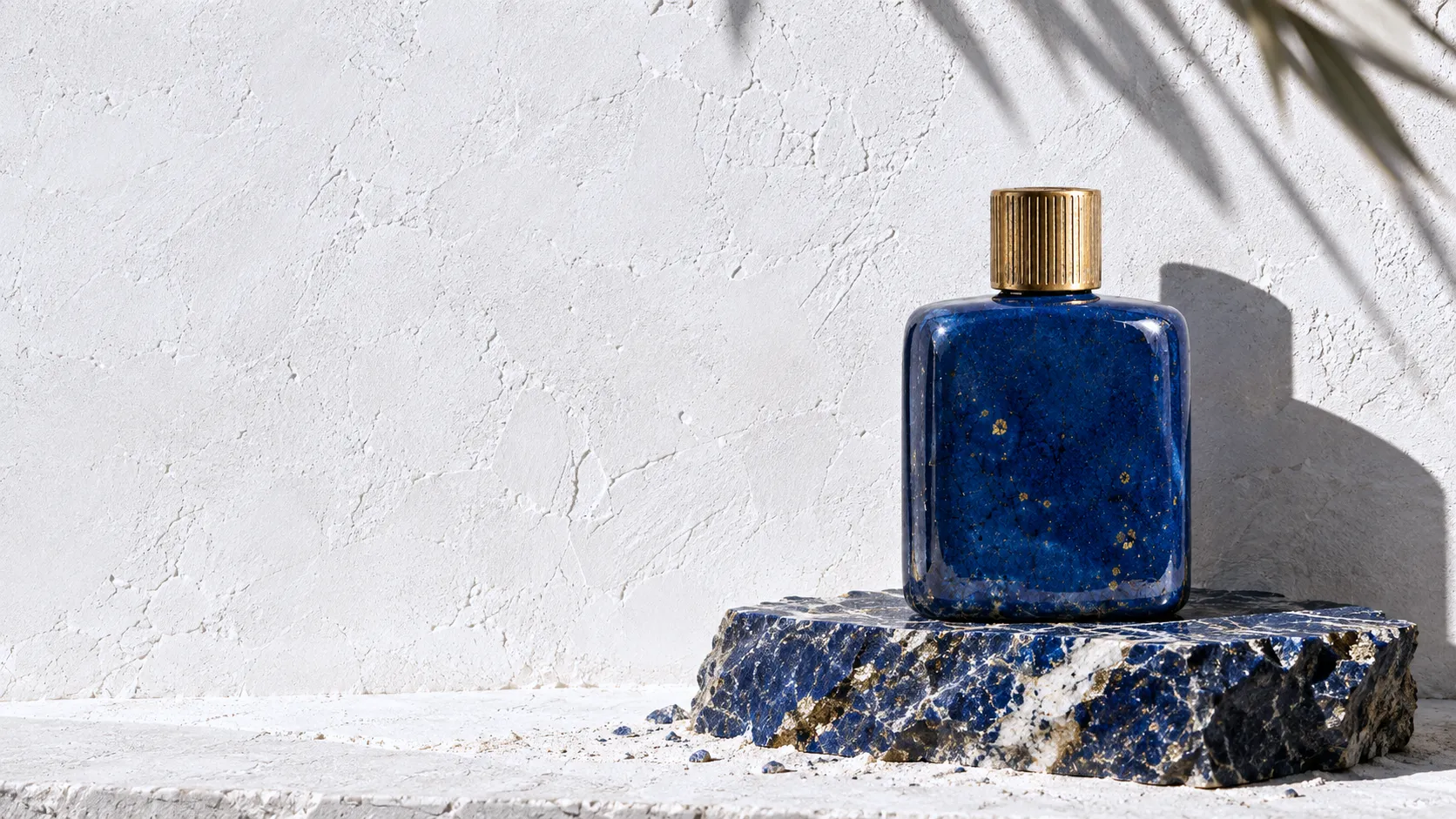 A heavy flacon in Egyptian-blue faience glaze with a gold cap, standing on raw lapis lazuli in hard afternoon sun