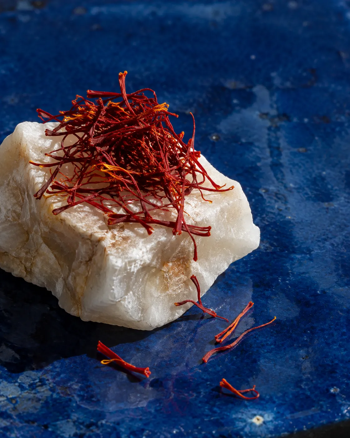 Dried saffron threads on white alabaster and a blue glazed tile